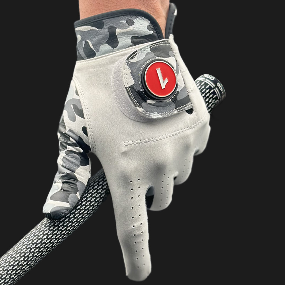 Image of a unique golf glove in camo with ball marker in red up close and a black background holding a golf club.