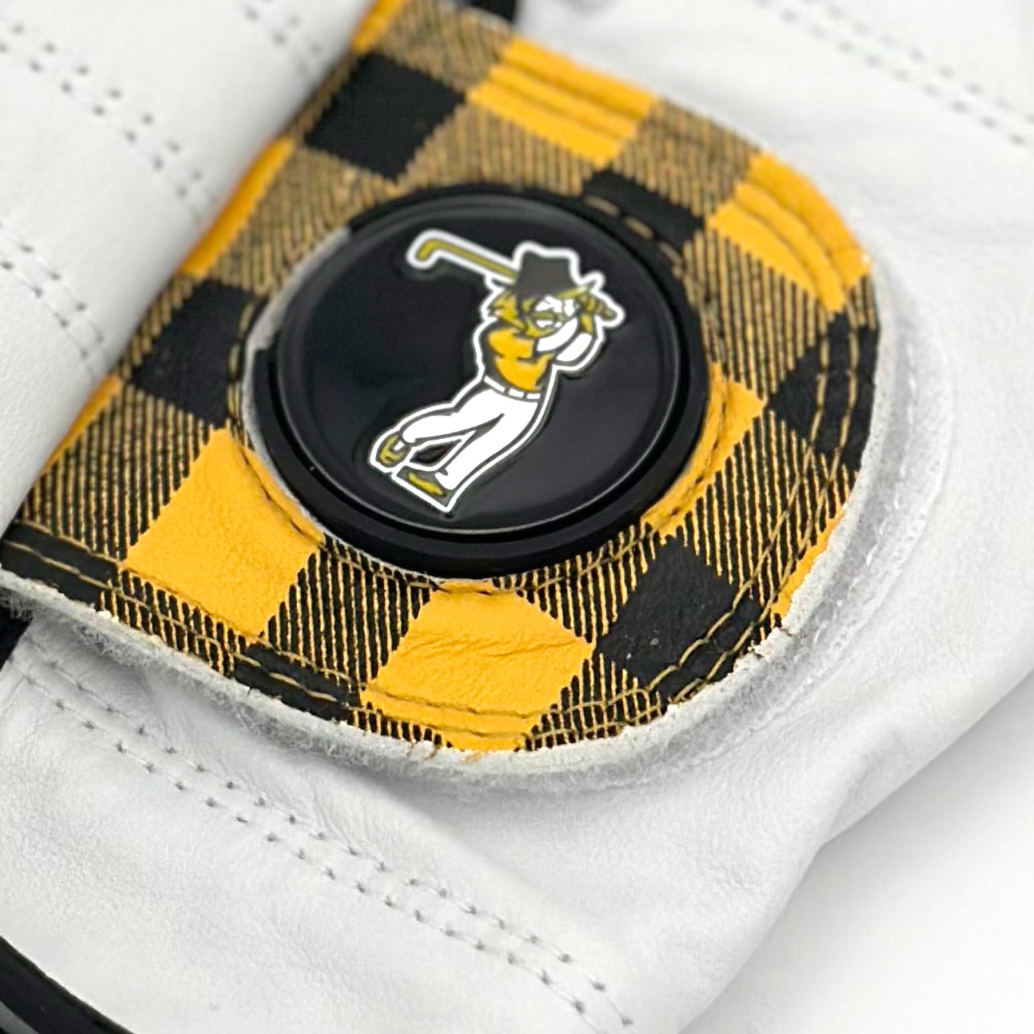 Close up of a customer golf glove with magnetic ball marker showcasing a yellow and black plaid pattern with a mountain man golfer as the ball marker logo.