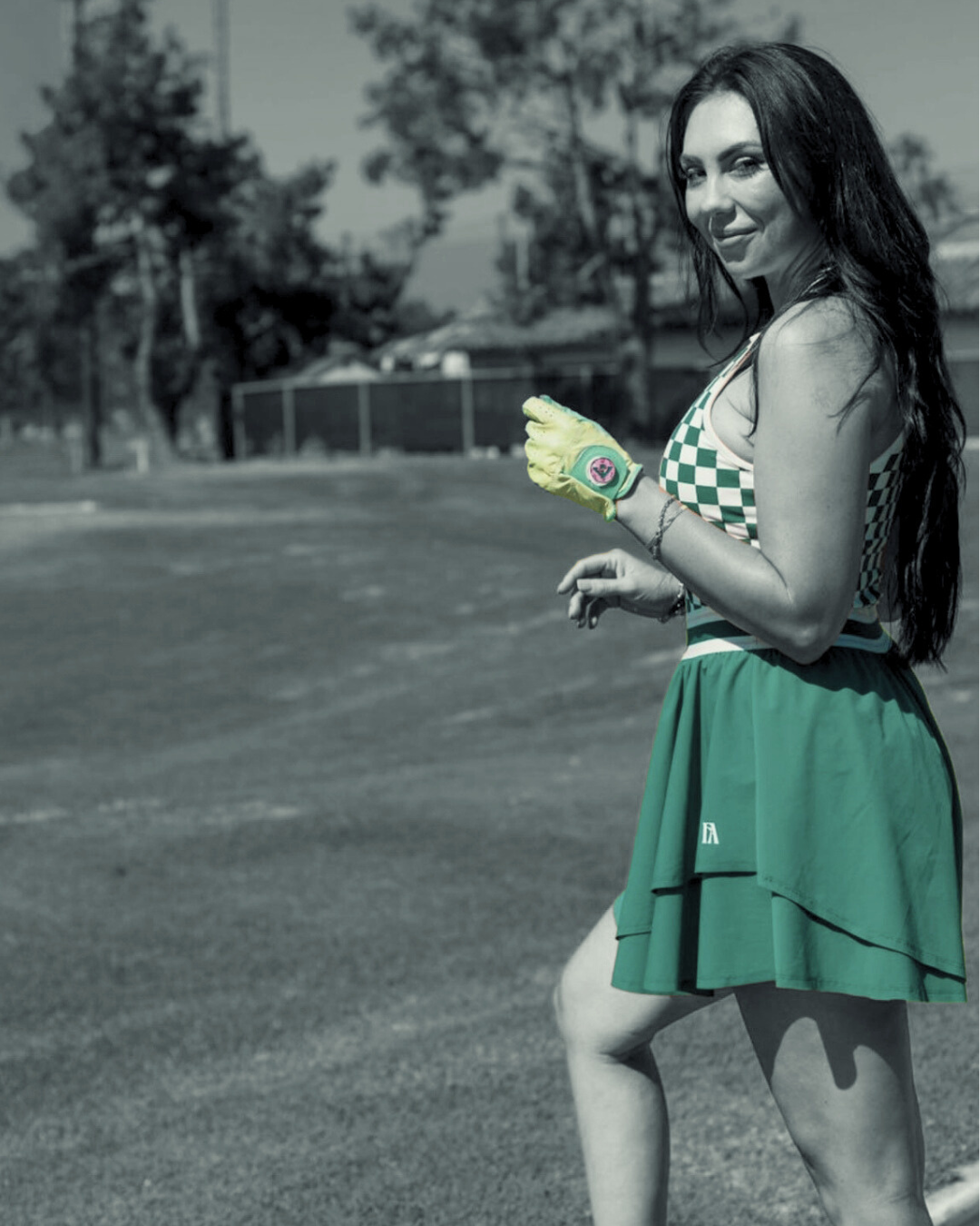 Woman in very stylish green skirt and checkered, accessorized with the Seaport Serenity, green golf glove with pink ball marker.  