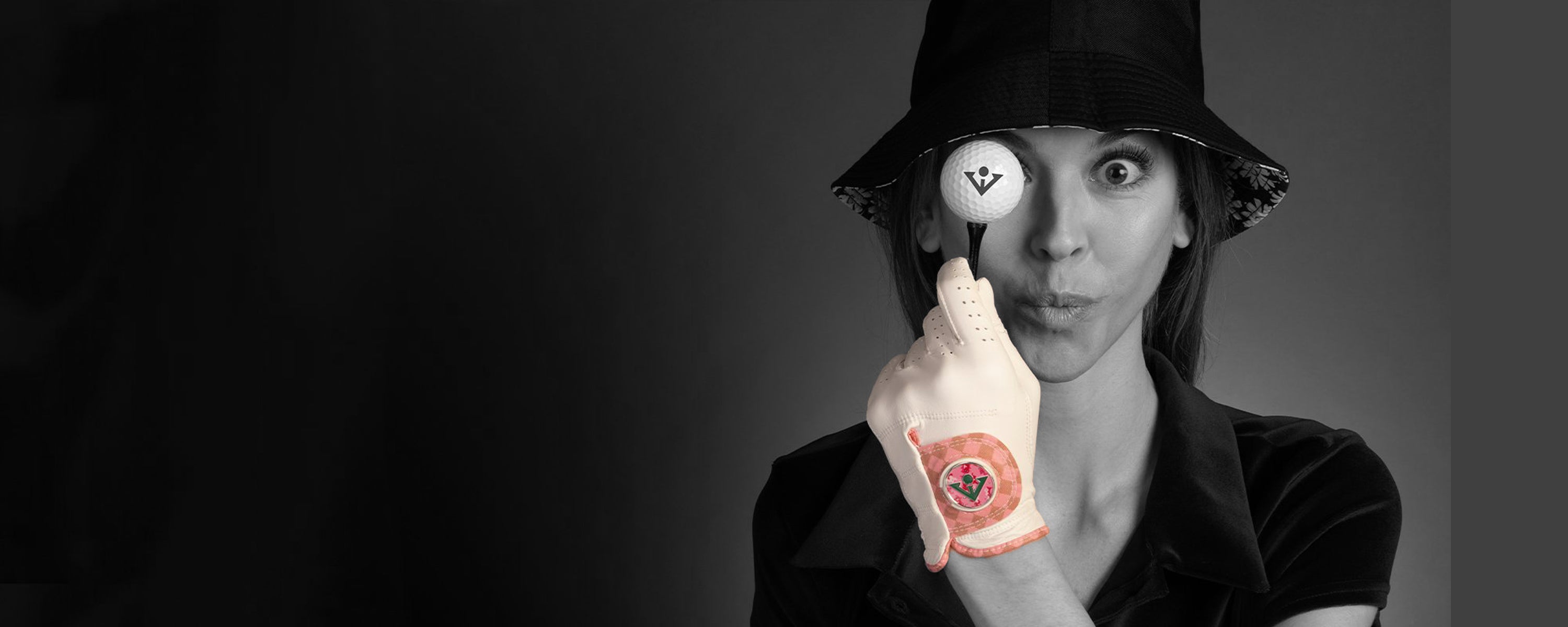 Women holding a tee and golf ball, making a goofy face wearing a fancy golf glove in pink and white by VivanTee Golf.