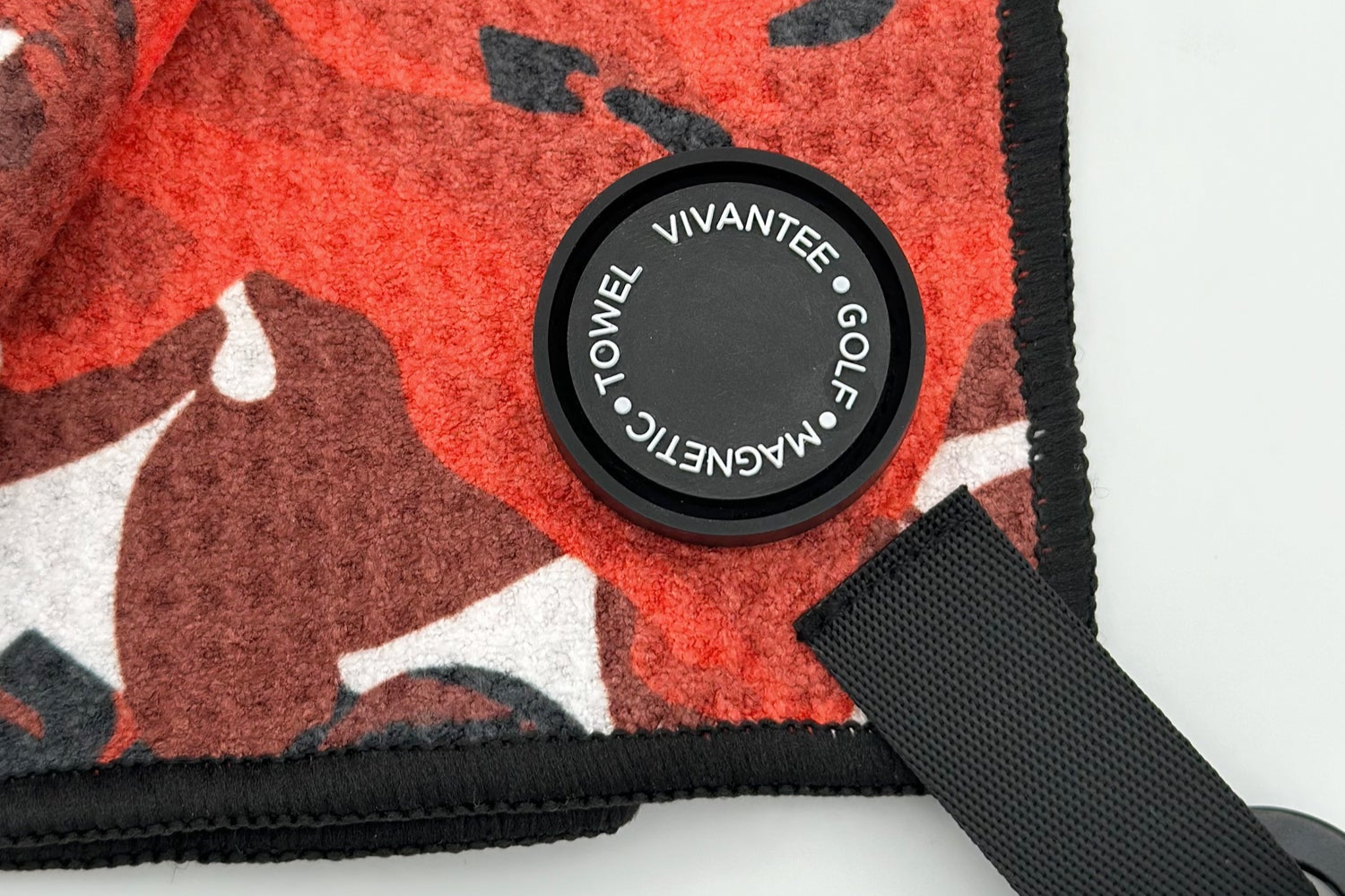 Close up of VivanTee magnet attachment to Central Petal golf towel in red and black.