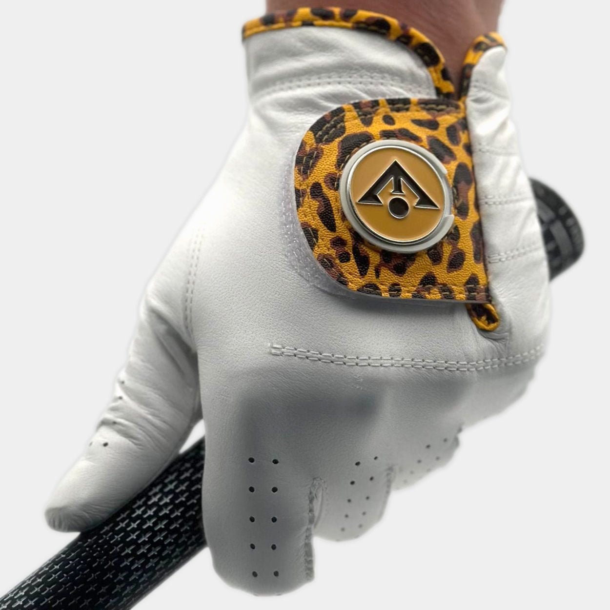 Close up of a men's cheetah print golf glove with brown and black magnetic ball marker.