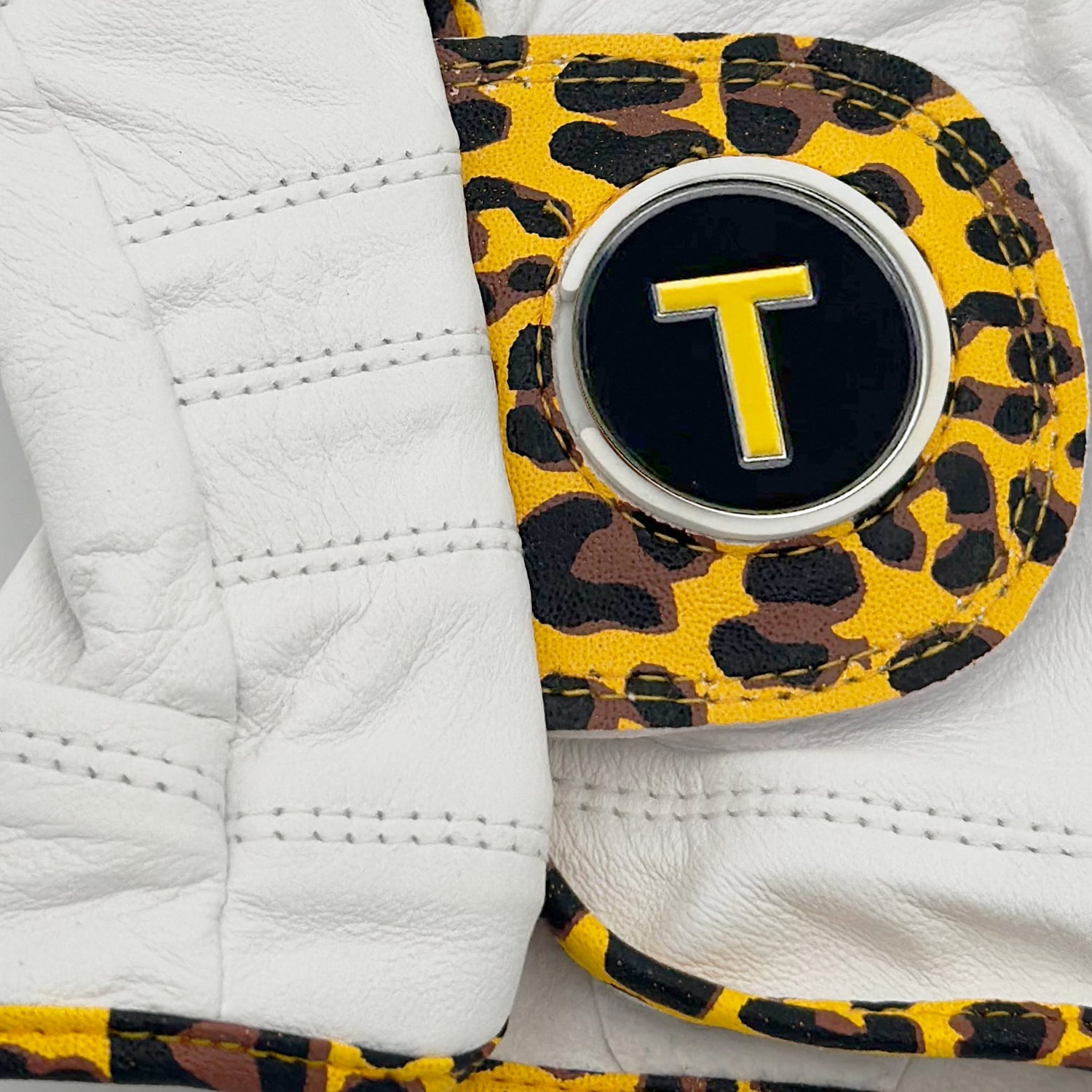 Men's Cheetah print golf glove with VivanTee Golf T Train ball marker close up image.