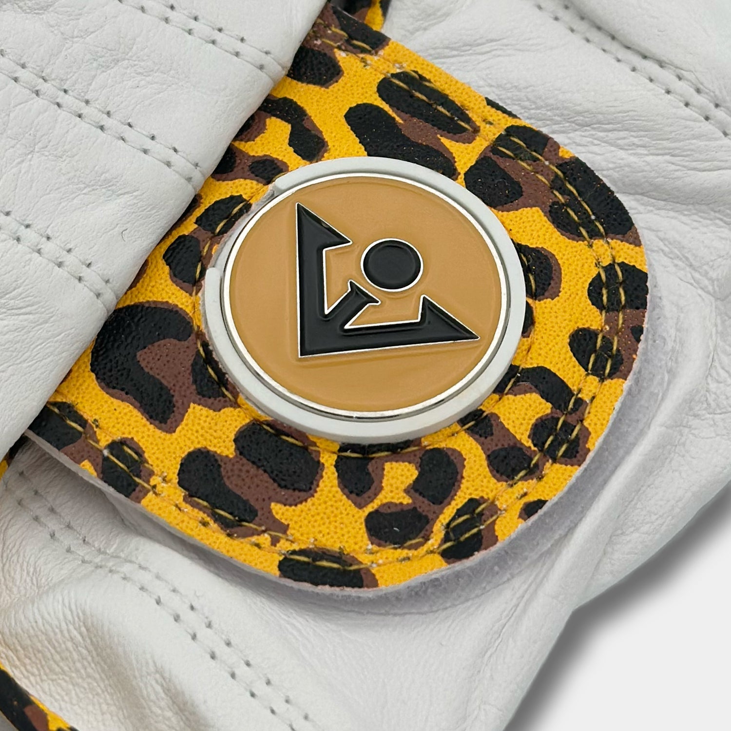 Close-up of a VivanTee Cabretta leather golf glove with a yellow leopard print design and a black logo ball marker, blending style and performance.