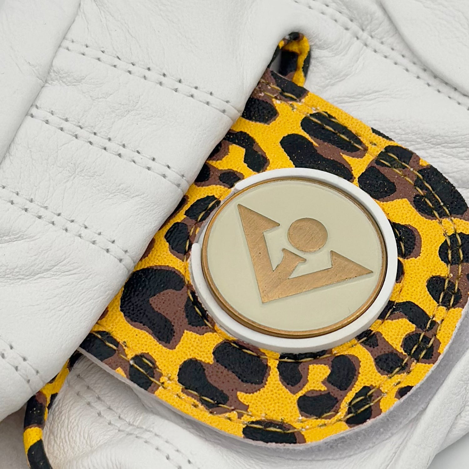 Close up of Cheetah print golf glove with a cream and copper ball marker by VivanTee Golf.