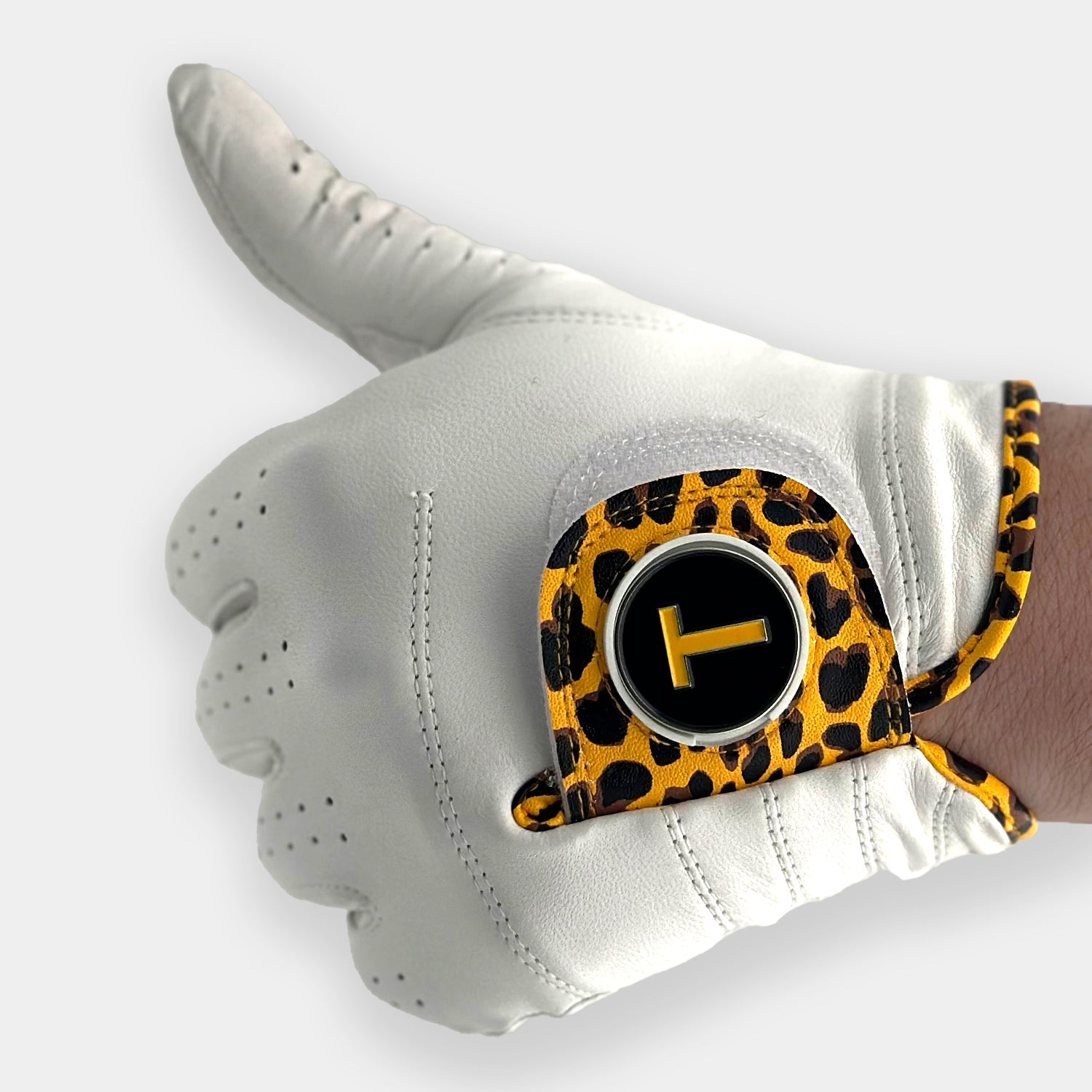 Cheetah print golf glove close up with T train ball marker by VivanTee golf giving a thumbs up.