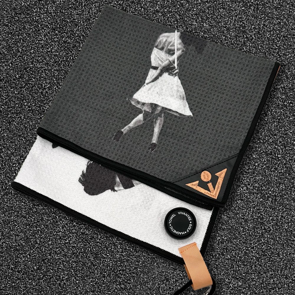 Magnetic golf towel in black and white with woman in dress holding a golf club and an orange VivanTee golf logo.  