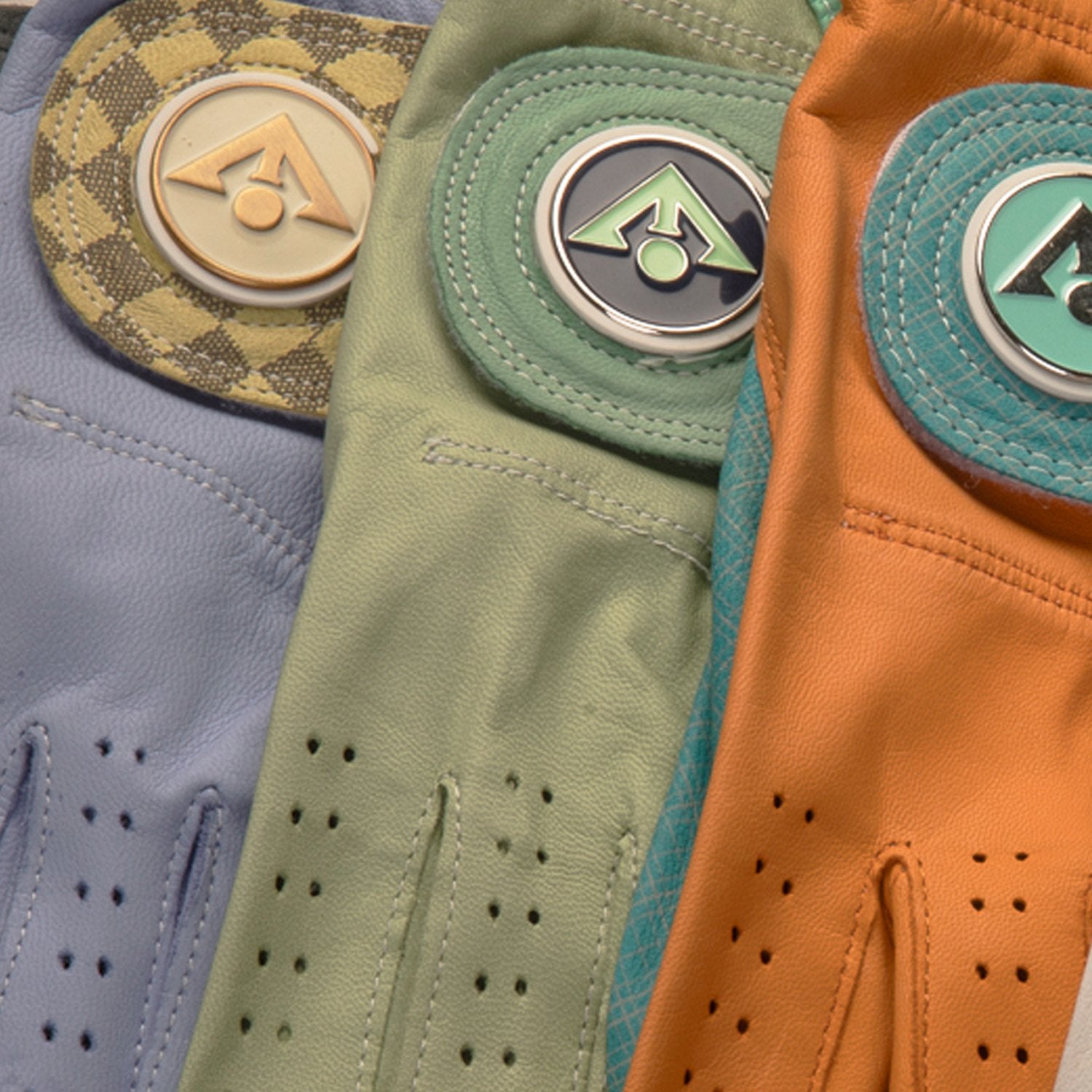 Close up shot of premium women's leather golf gloves in purple, green, and orange side by side.