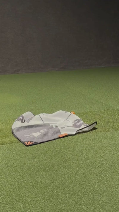 Video of VivanTee magnetic golf towel in black, white, and orange on the ground and being picked up by a golfer with their golf club.