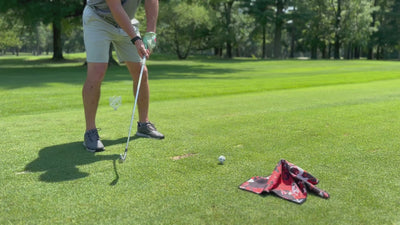 Golfer taking practice swings and then using his club to pick up his magnetic golf towel showing the convenience and vibrant colors.