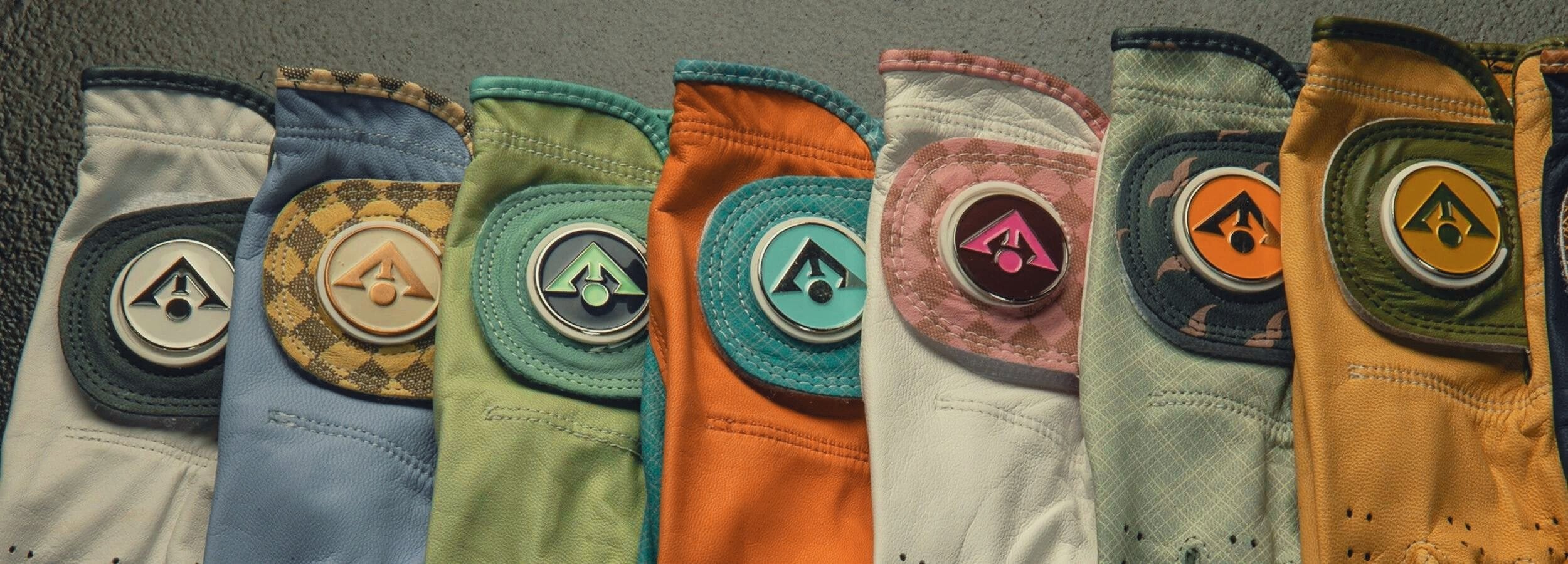 Unique golf gloves with ball markers laid out across each other in various colors and styles, showing the uniqueness of each design.