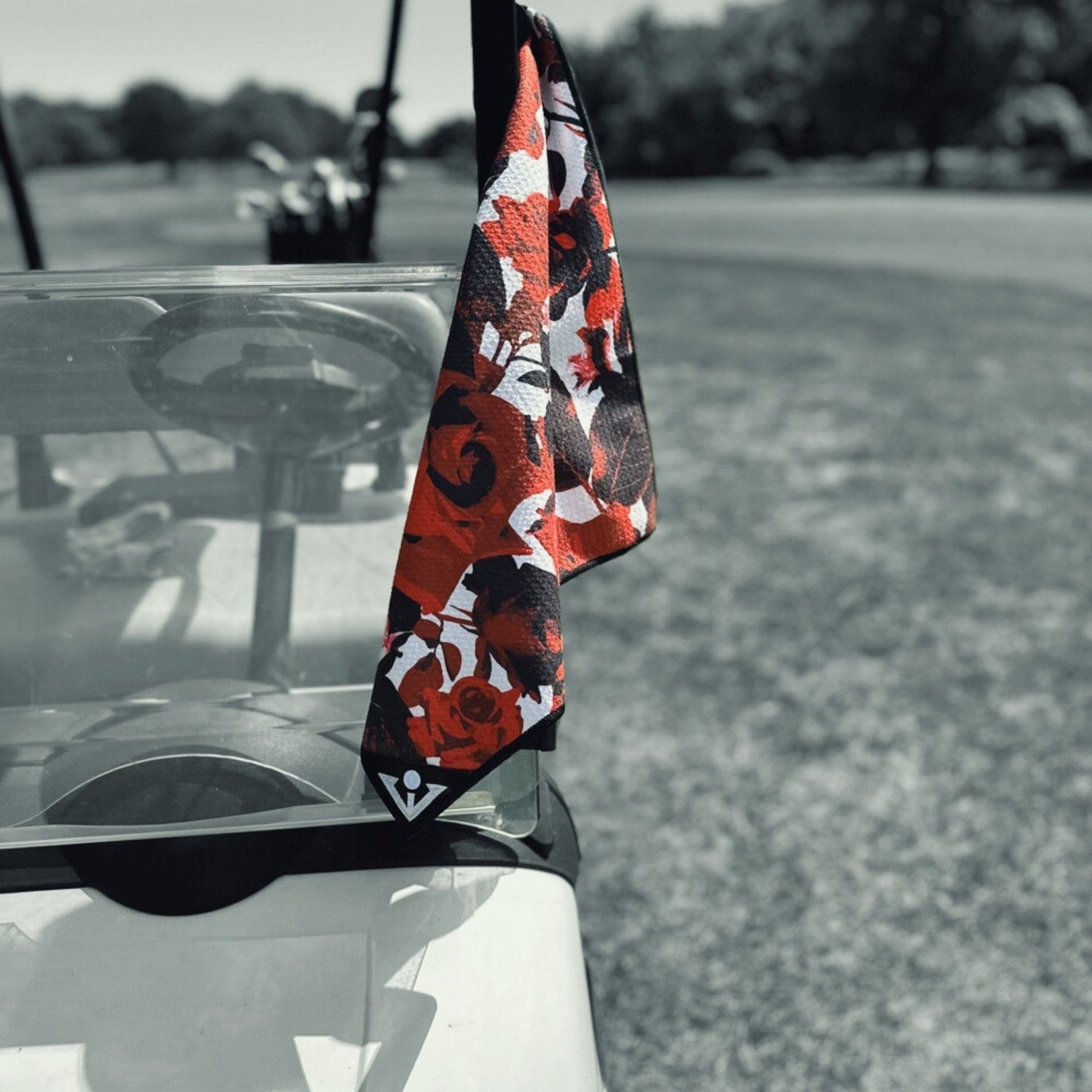 Magnetic golf towel in floral print attache to a golf cart, with a monochromatic background. 