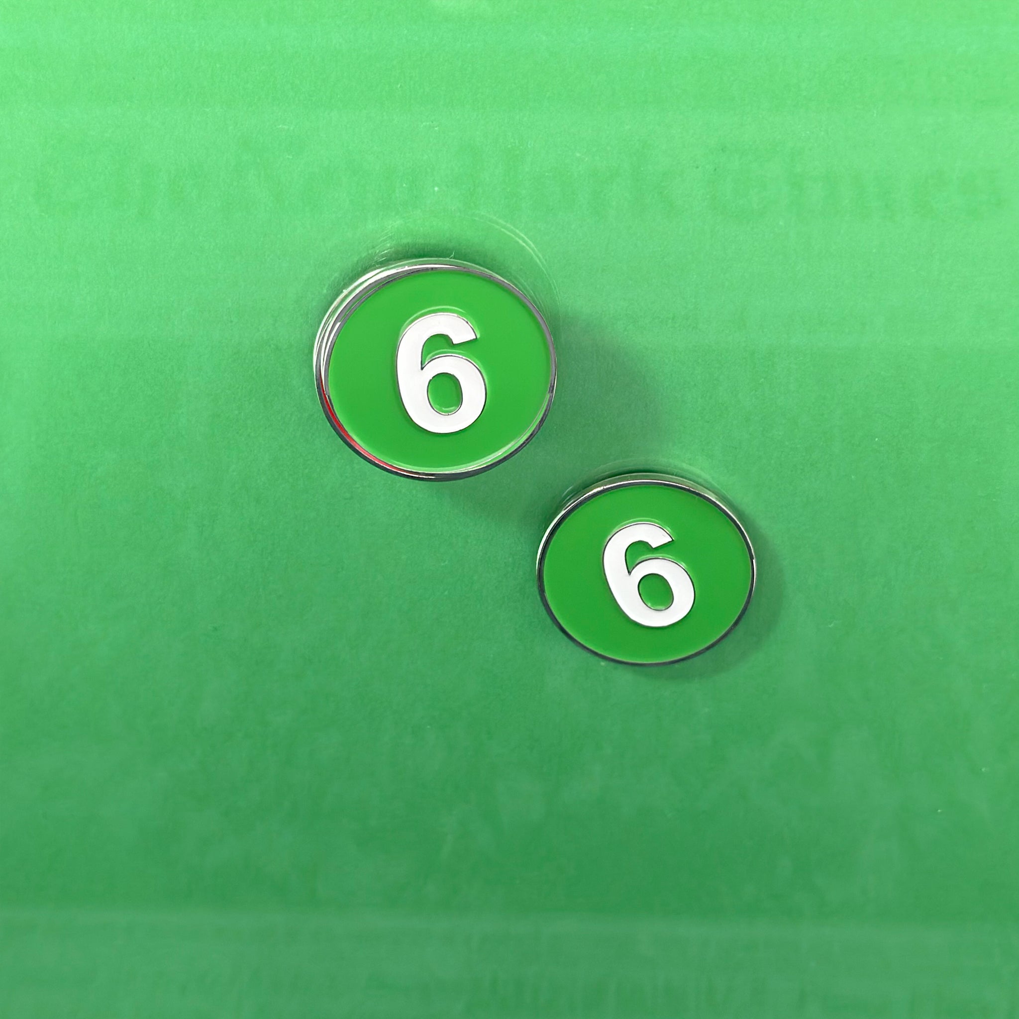 6 train magnetic golf ball marker with New York Times Backdrop over green.