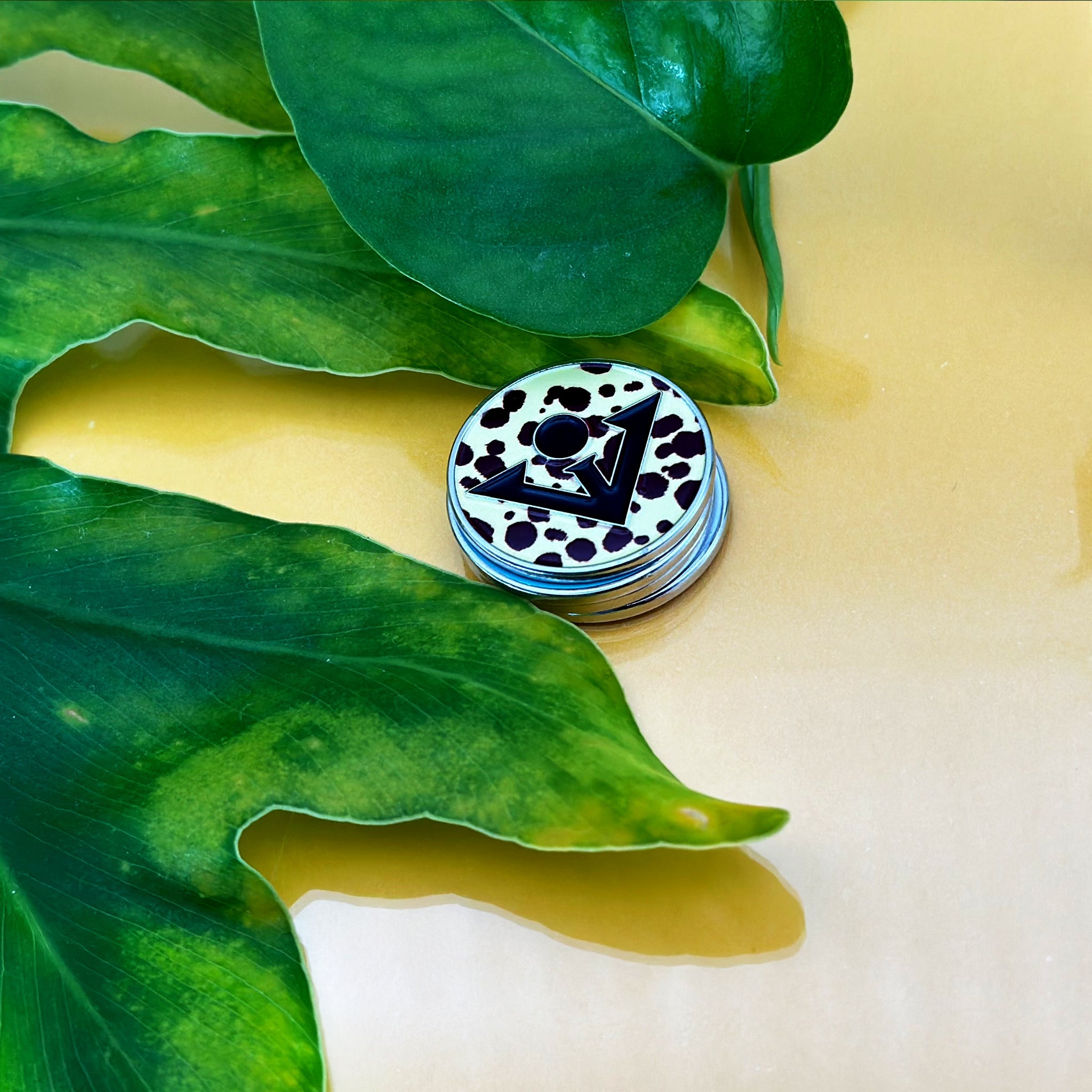 Cheetah print magnetic golf ball marker with leaves and gold backdrop.