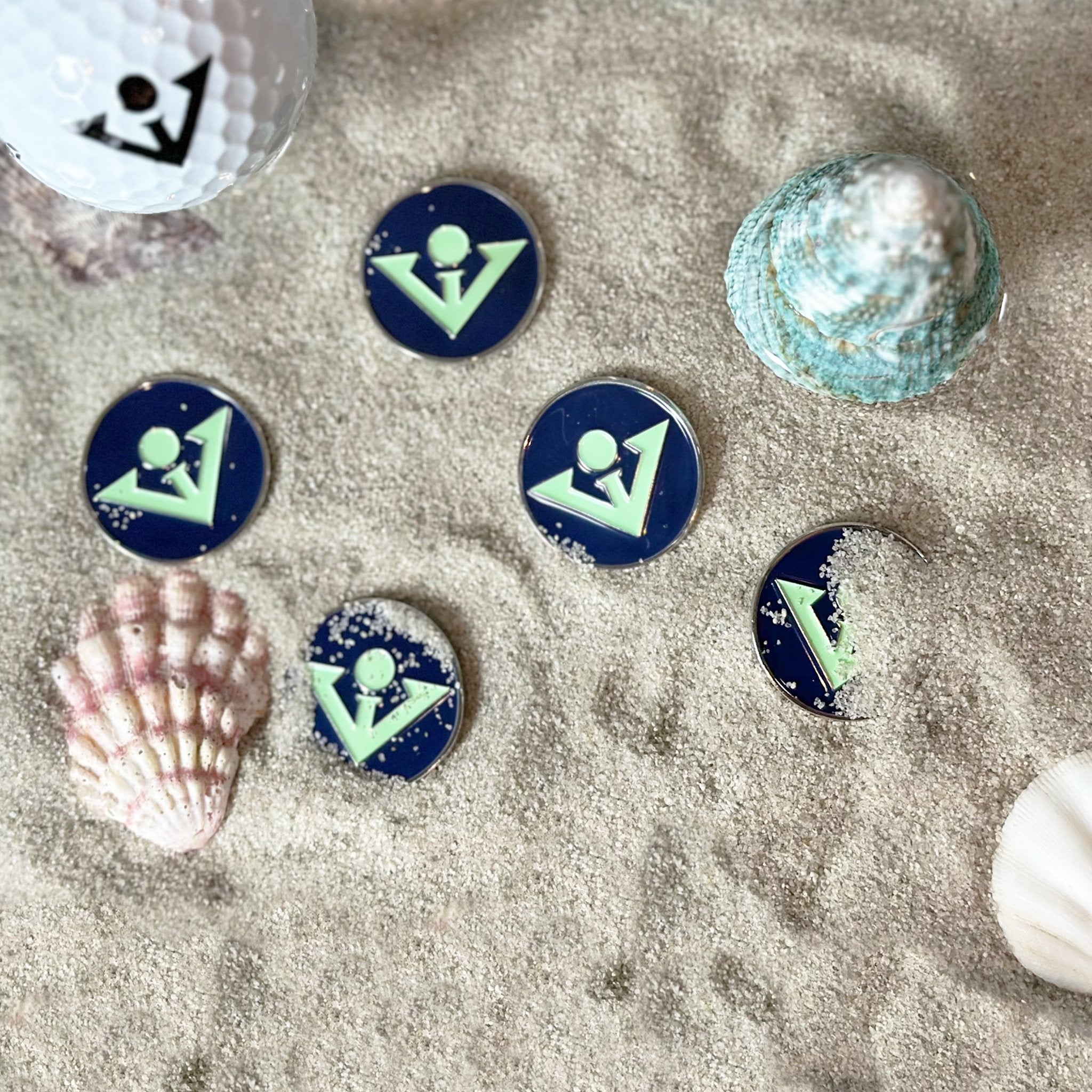 Seafoam Blue Ball Marker surrounded by sand, water and seashells in an elegant fashion